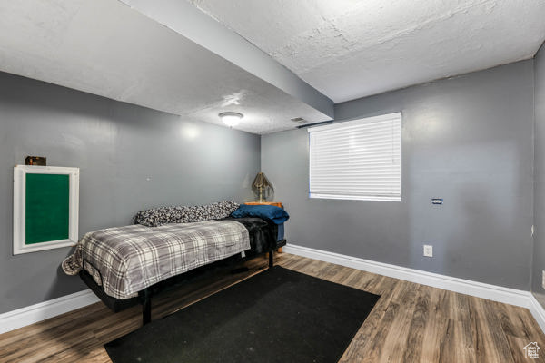 Bedroom featuring baseboards, wood finished floors, and a textured ceiling