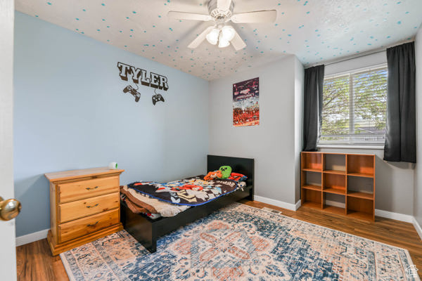 Bedroom with baseboards, wood finished floors, and a ceiling fan
