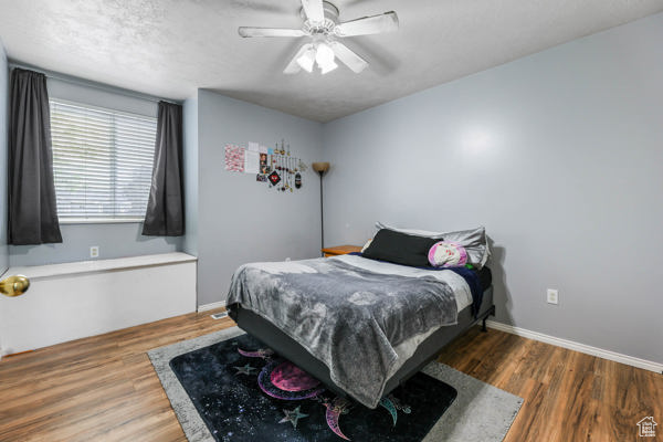 Bedroom with wood finished floors, baseboards, and a ceiling fan
