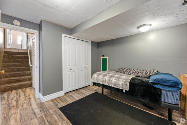 Bedroom featuring wood finished floors, baseboards, a closet, and a textured ceiling