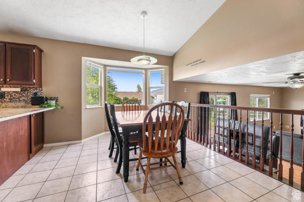 Dining area featuring light tile patterned floors, plenty of natural light, baseboards, and lofted ceiling