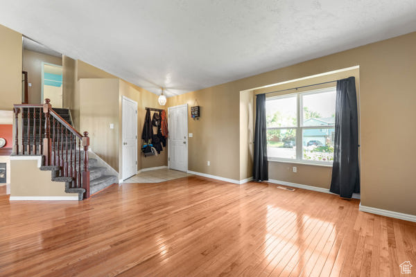 Unfurnished living room with wood-type flooring, baseboards, and stairs