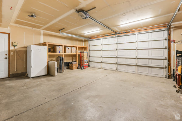 Garage with freestanding refrigerator and a garage door opener