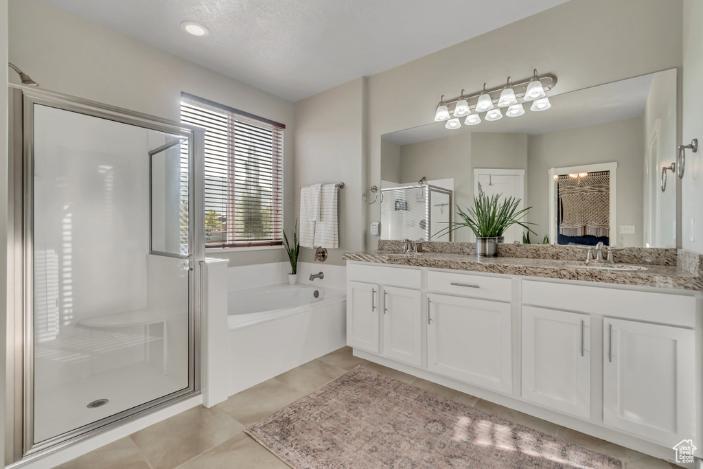 Full bathroom featuring a stall shower, double vanity, a garden tub, and tile patterned flooring