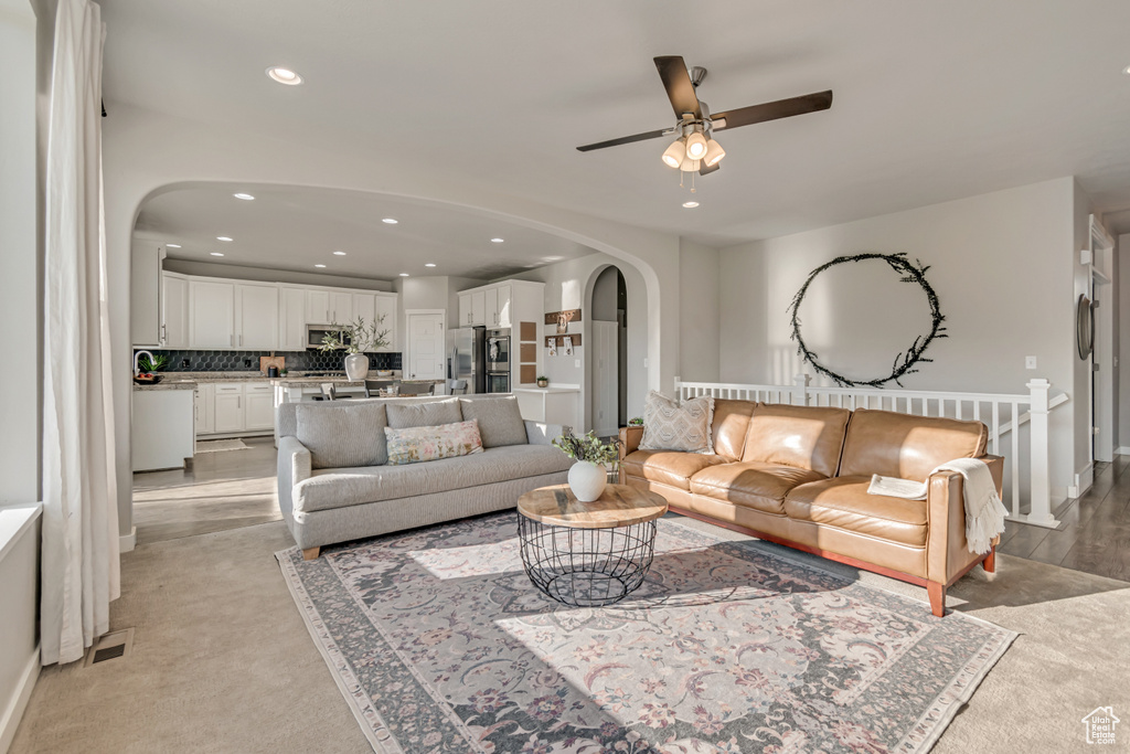 Living room with arched walkways, a ceiling fan, recessed lighting, and baseboards