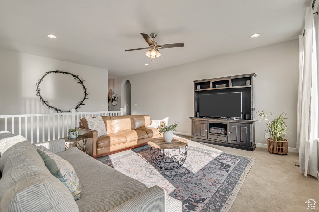 Living area with arched walkways, ceiling fan, light carpet, recessed lighting, and baseboards