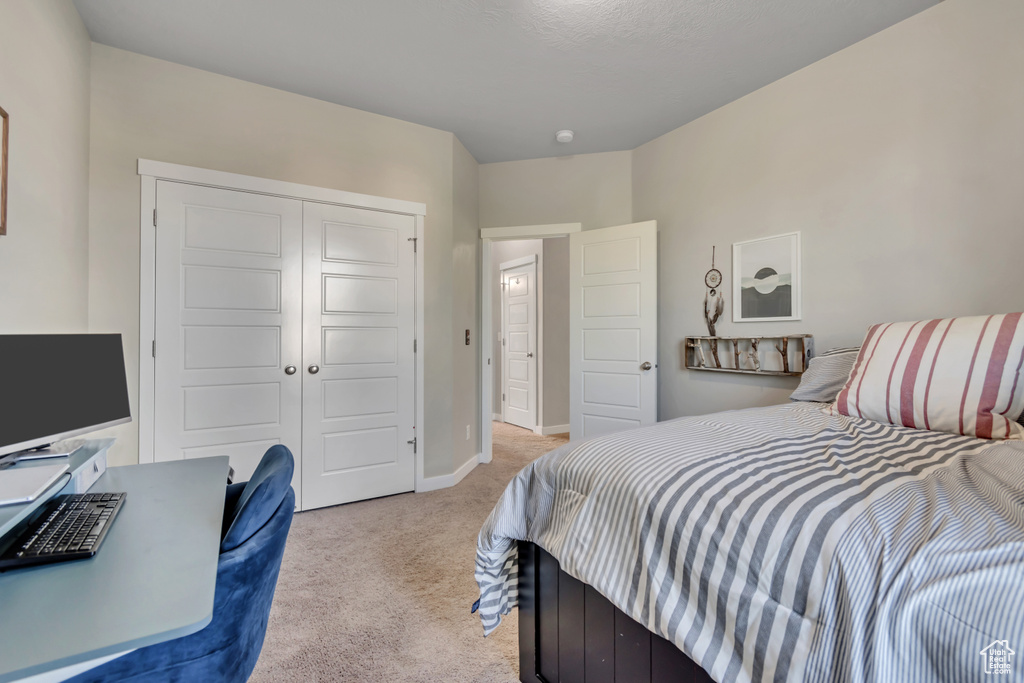 Bedroom with light colored carpet, a closet, and baseboards