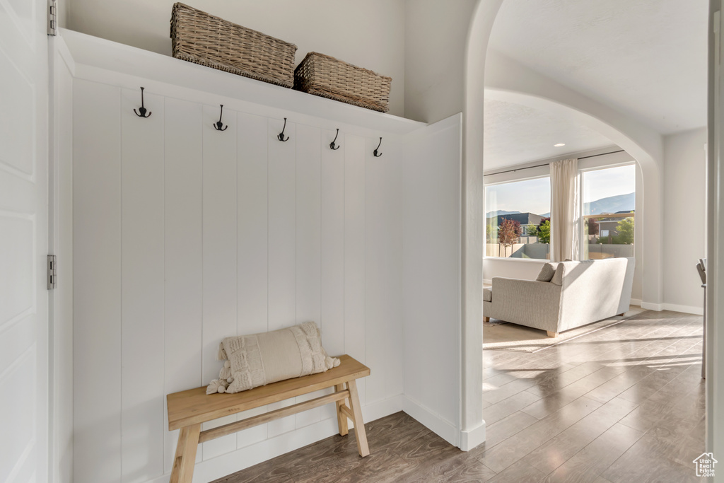 Mudroom with arched walkways, baseboards, and wood finished floors