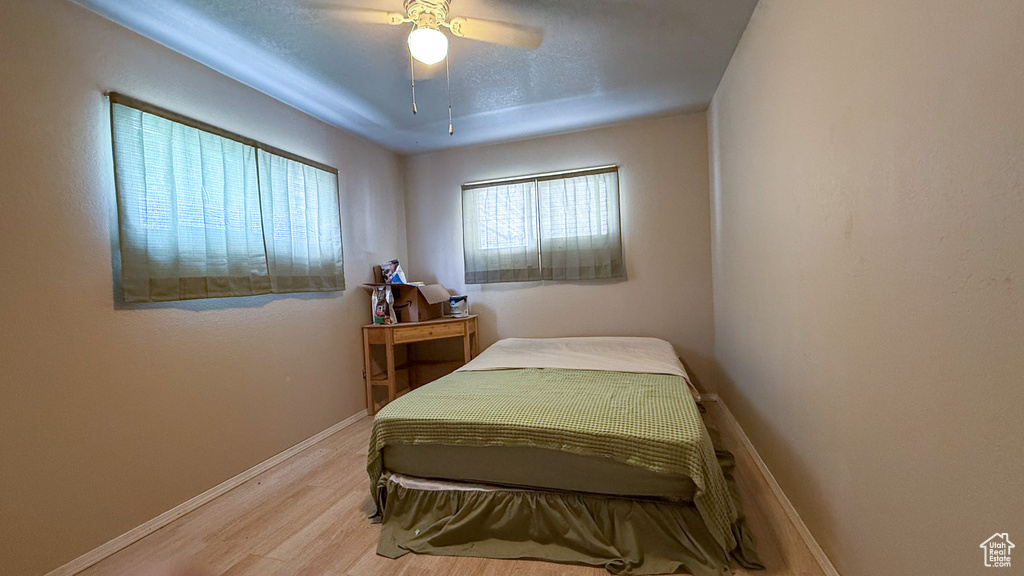 Bedroom with light wood finished floors, baseboards, and ceiling fan