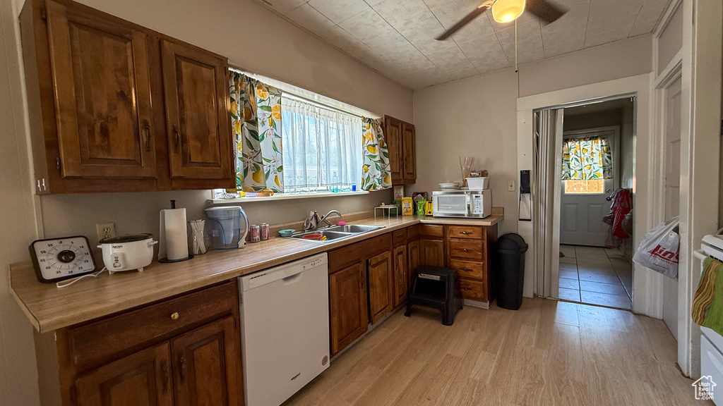 Kitchen featuring white appliances, a sink, plenty of natural light, and light wood-type flooring