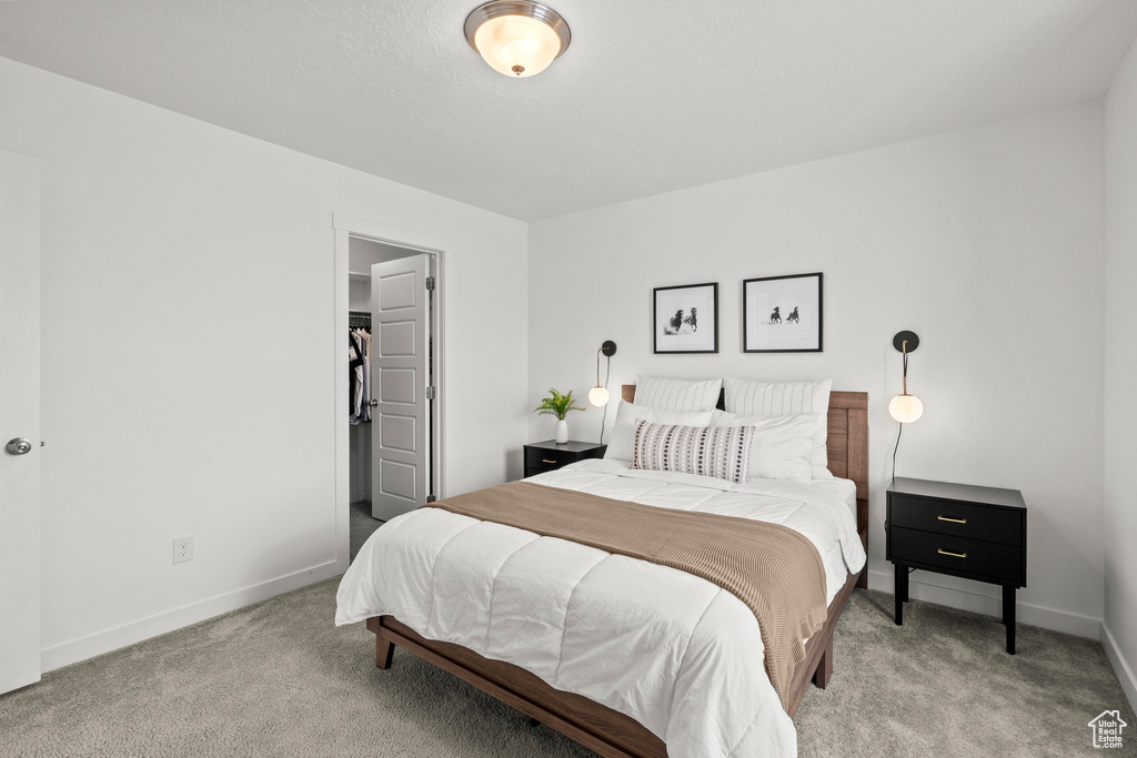 Bedroom with carpet, baseboards, and a walk in closet
