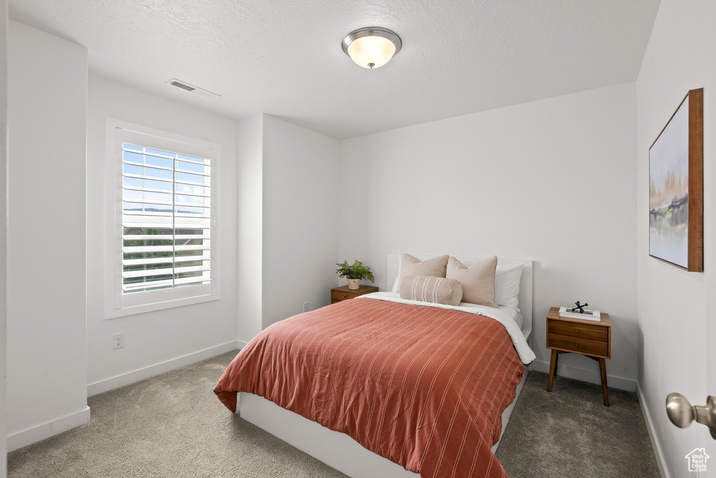 Bedroom with carpet flooring, baseboards, and a textured ceiling
