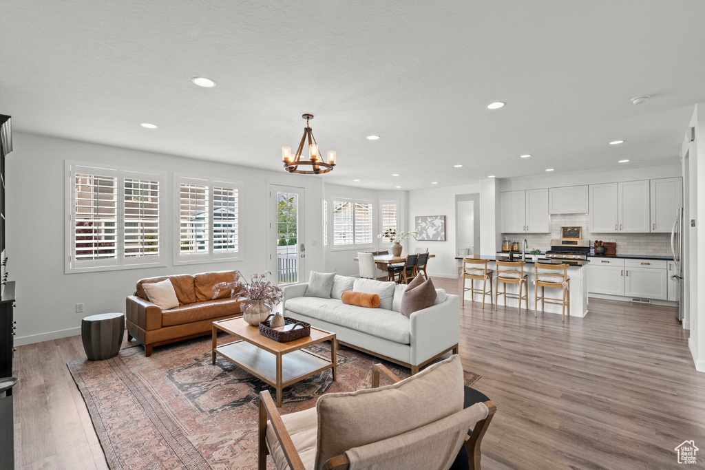 Living room featuring a chandelier, light wood-style floors, recessed lighting, and baseboards