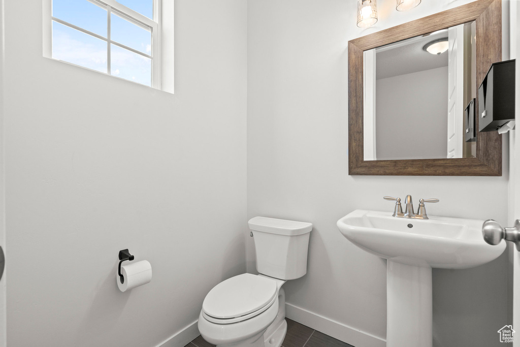Half bathroom featuring baseboards, toilet, and a sink