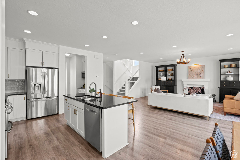 Kitchen with stainless steel appliances, dark countertops, a sink, recessed lighting, and a kitchen bar