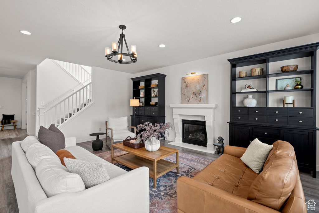 Living area featuring a chandelier, stairway, wood finished floors, recessed lighting, and a glass covered fireplace