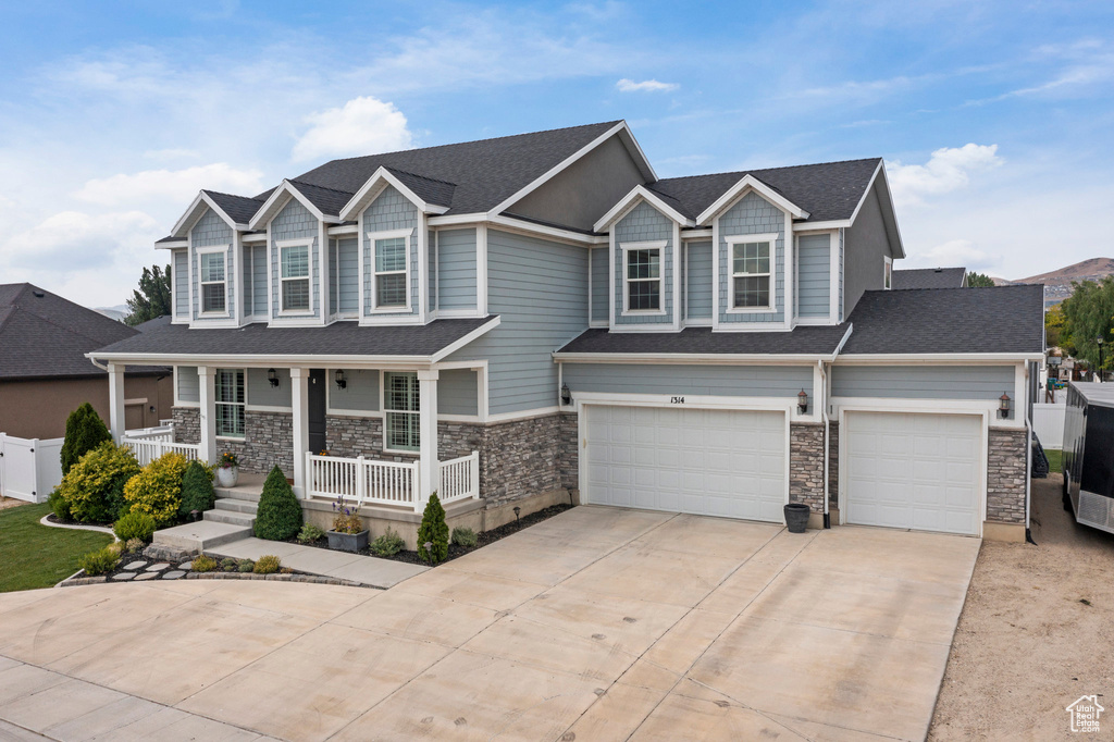 Craftsman house featuring a porch, concrete driveway, stone siding, an attached garage, and roof with shingles