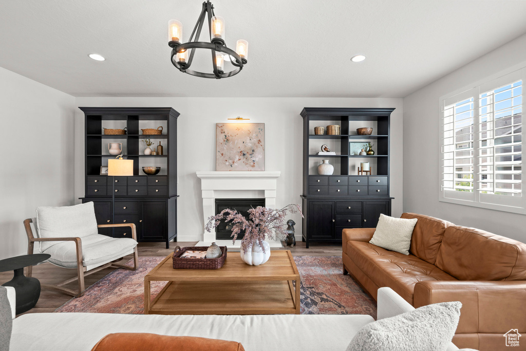 Living area featuring a chandelier, wood finished floors, a fireplace with raised hearth, and recessed lighting