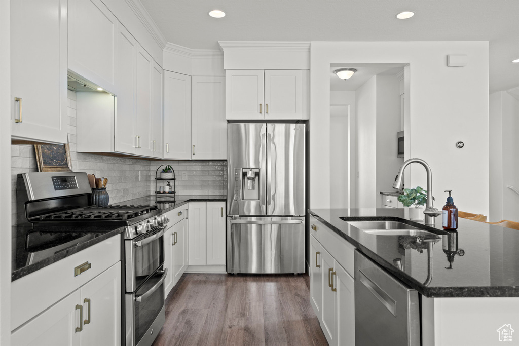 Kitchen with appliances with stainless steel finishes, a sink, an island with sink, dark stone counters, and recessed lighting