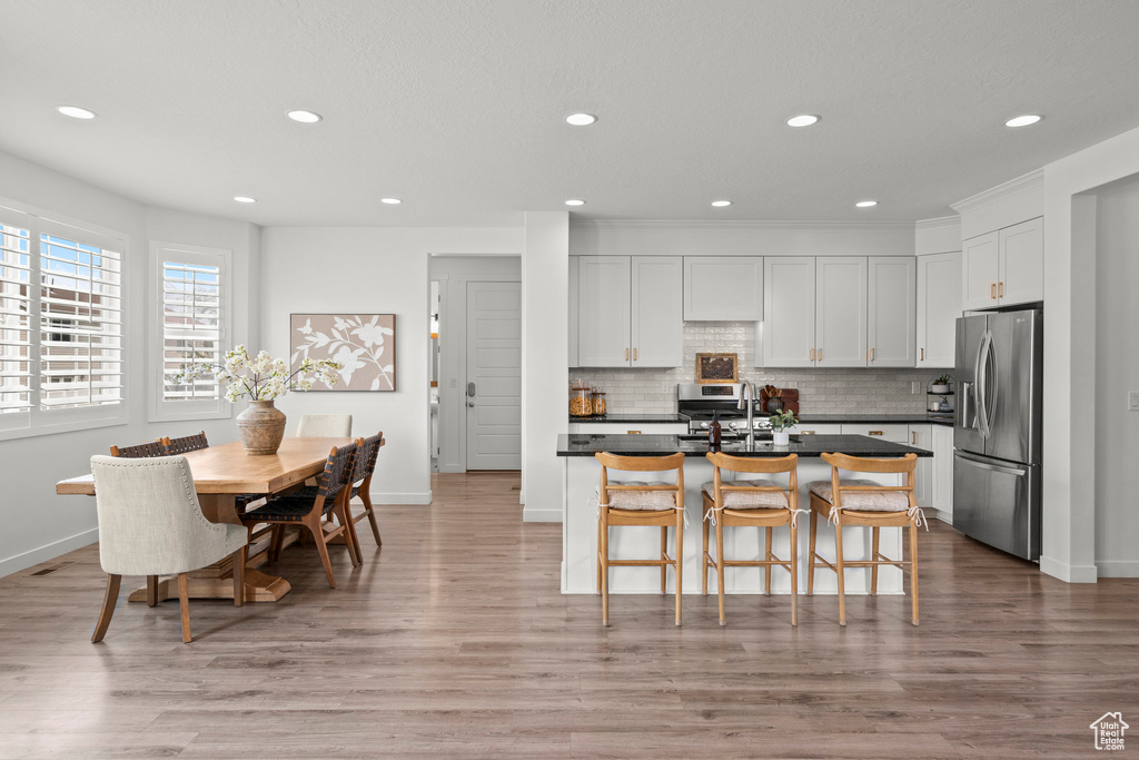 Kitchen with stainless steel fridge with ice dispenser, dark countertops, recessed lighting, decorative backsplash, and baseboards