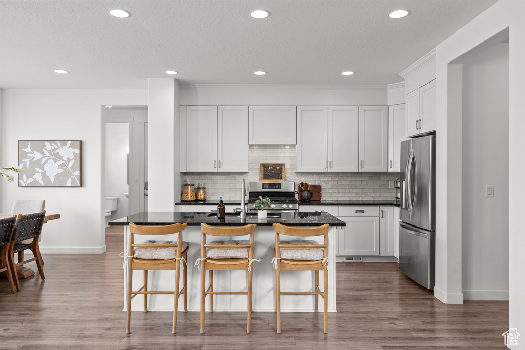 Kitchen with appliances with stainless steel finishes, baseboards, dark countertops, backsplash, and recessed lighting