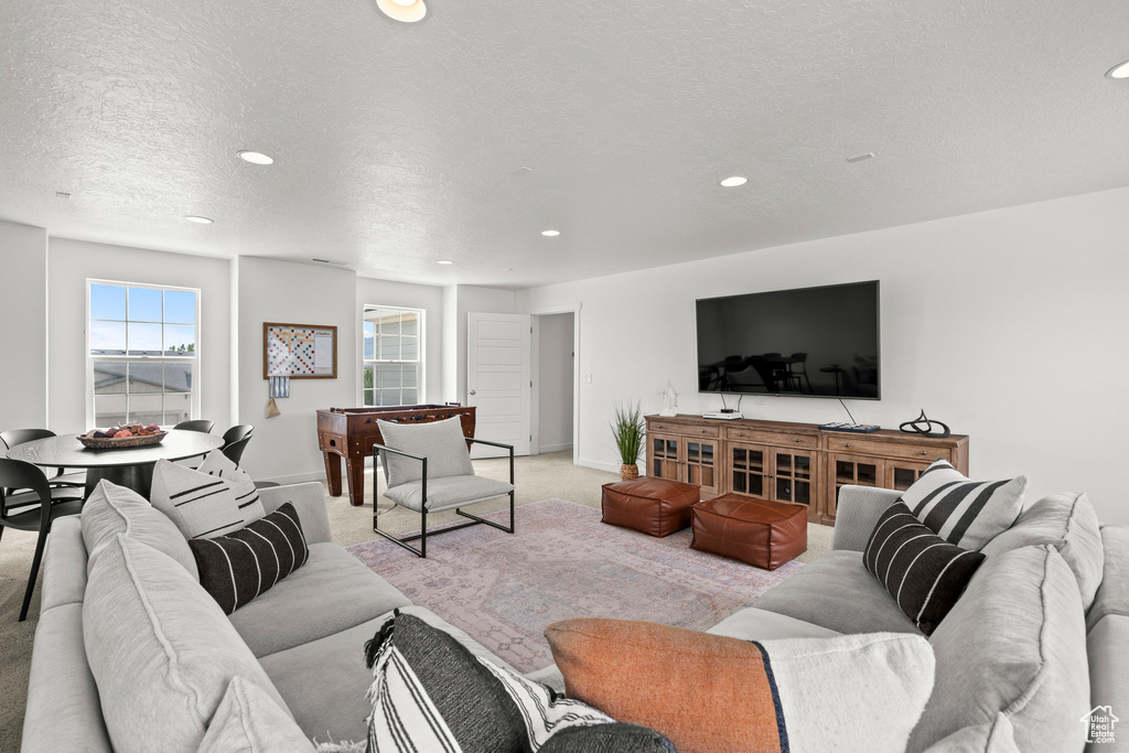 Living area featuring light colored carpet, recessed lighting, a textured ceiling, and baseboards