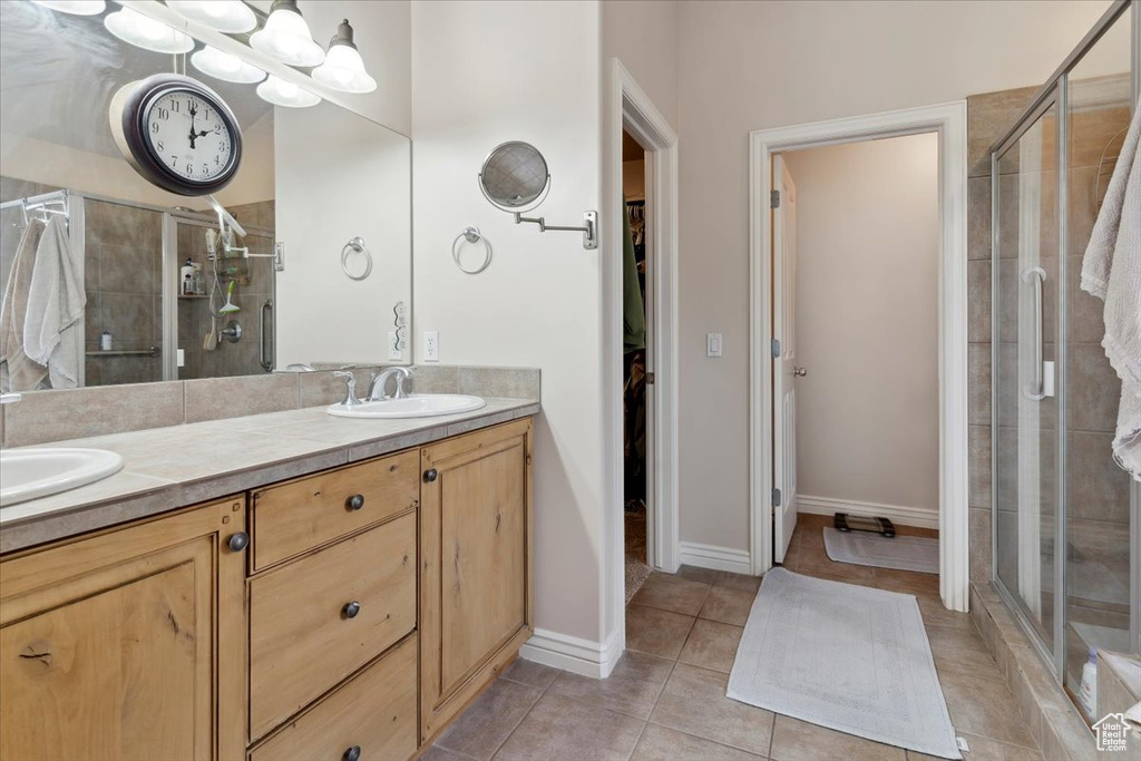 Full bathroom featuring a spacious closet, a stall shower, and double vanity