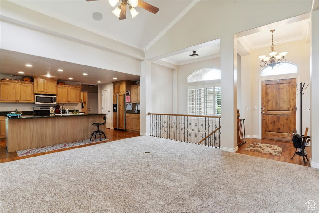 Kitchen with stainless steel appliances, dark countertops, crown molding, high vaulted ceiling, and ceiling fan
