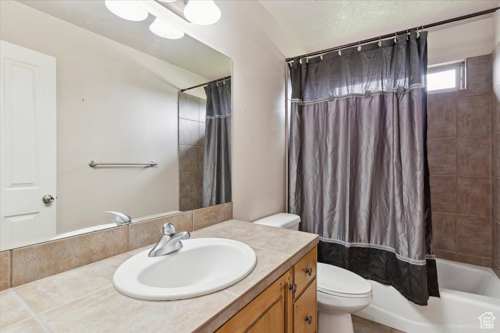 Full bathroom featuring toilet, vanity, and shower / bath combination with curtain
