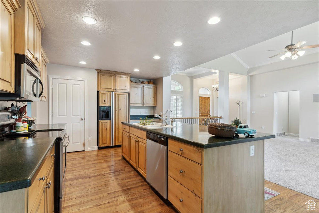 Kitchen with appliances with stainless steel finishes, a sink, dark countertops, baseboards, and ceiling fan