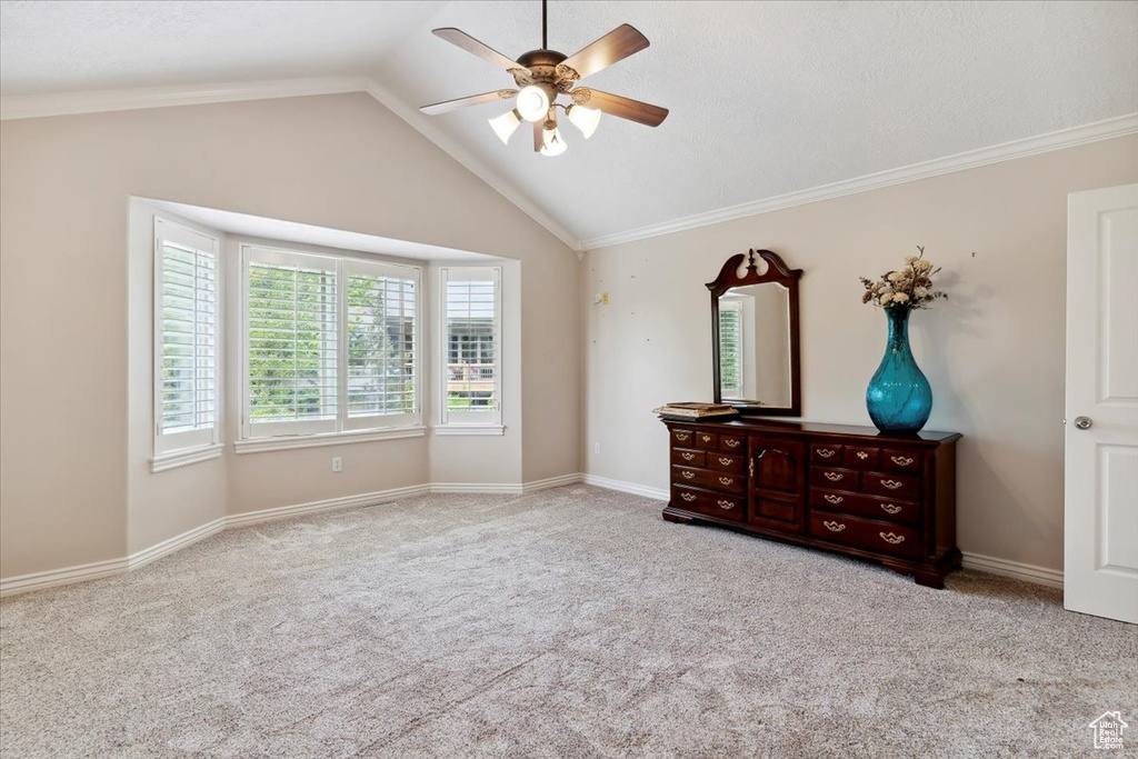 Unfurnished bedroom featuring vaulted ceiling, carpet flooring, ornamental molding, a ceiling fan, and baseboards