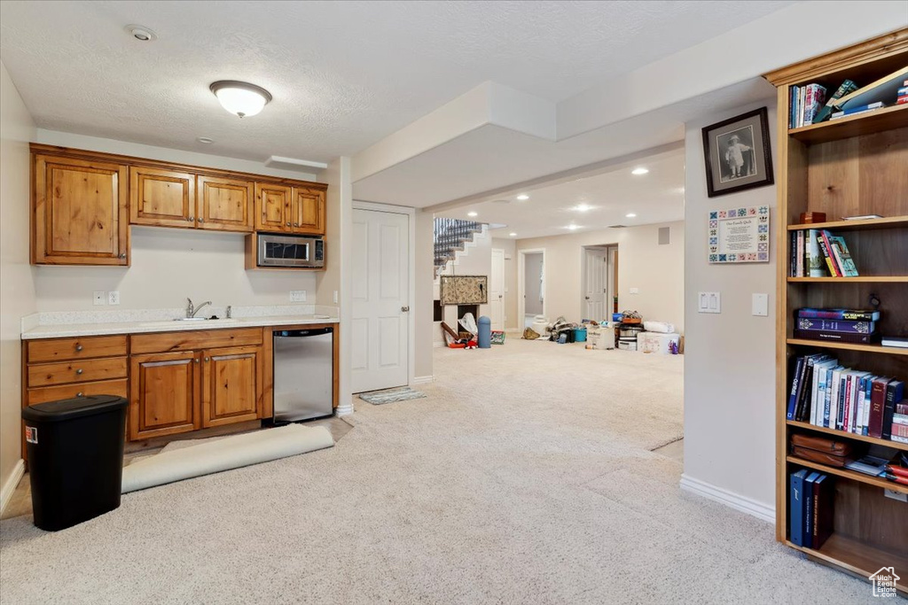 Kitchen featuring appliances with stainless steel finishes, light carpet, brown cabinets, light countertops, and recessed lighting