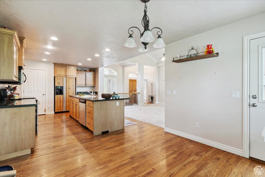 Kitchen with appliances with stainless steel finishes, light brown cabinets, dark countertops, a chandelier, and recessed lighting