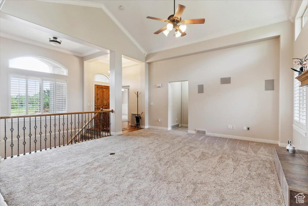 Unfurnished room featuring plenty of natural light, a ceiling fan, ornamental molding, baseboards, and high vaulted ceiling