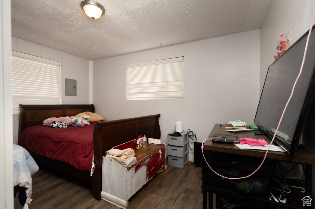 Bedroom featuring wood finished floors, a textured ceiling, and electric panel
