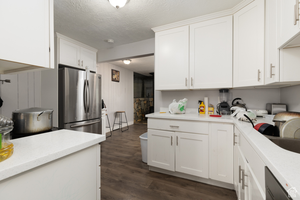 Kitchen featuring freestanding refrigerator, white cabinets, dark wood finished floors, and a textured ceiling