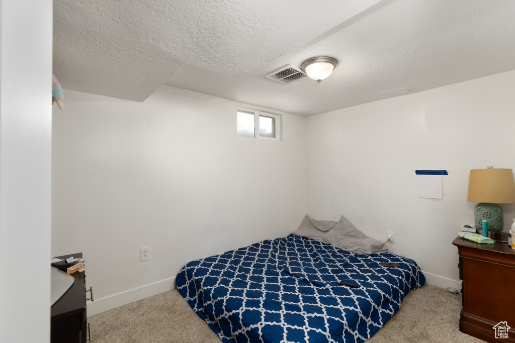 Bedroom featuring carpet flooring, baseboards, and a textured ceiling