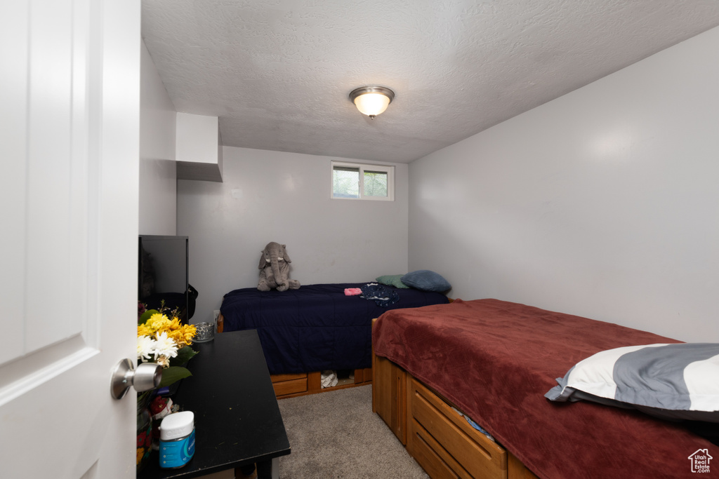 Bedroom featuring light colored carpet and a textured ceiling