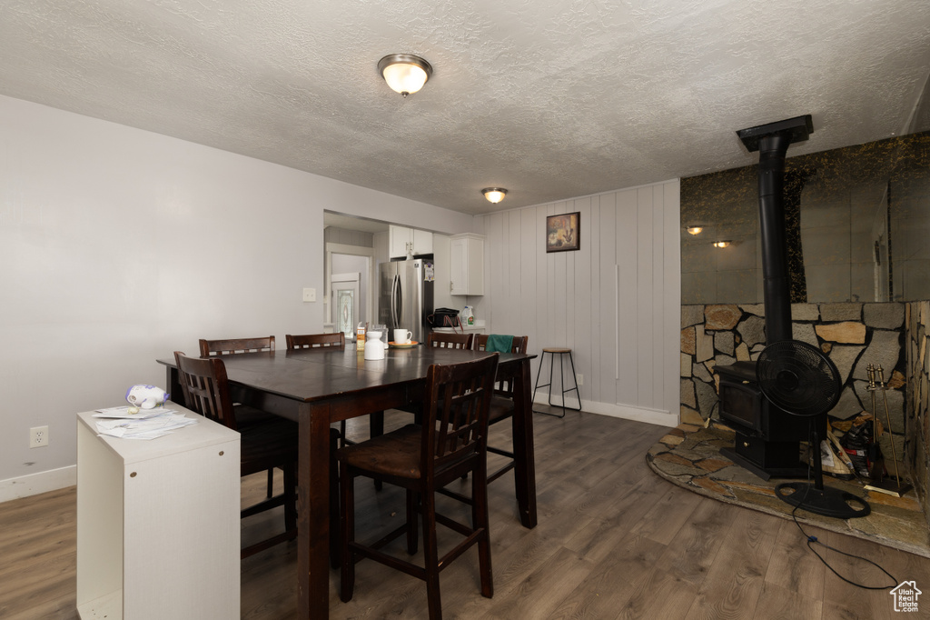 Dining space featuring baseboards, dark wood finished floors, a textured ceiling, and a wood stove