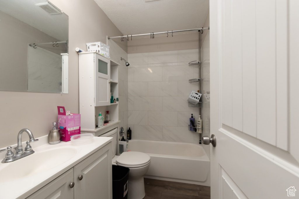 Bathroom featuring vanity, shower / tub combination, toilet, and wood finished floors