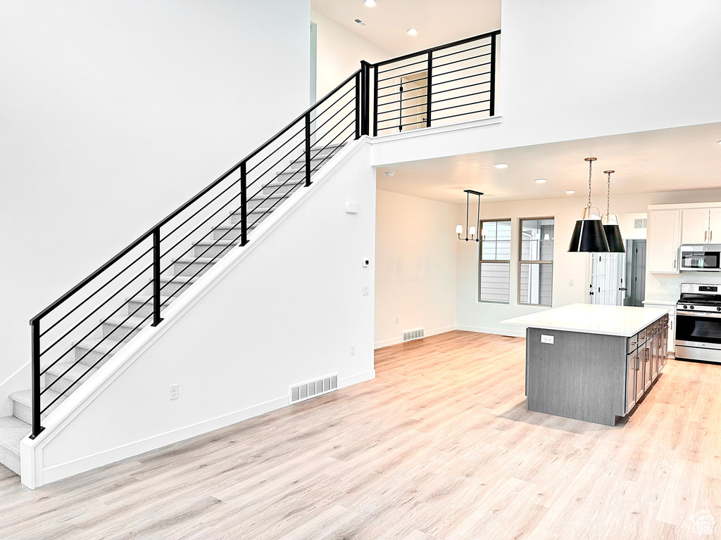 Kitchen featuring stainless steel appliances, light wood-type flooring, a kitchen island, recessed lighting, and light countertops