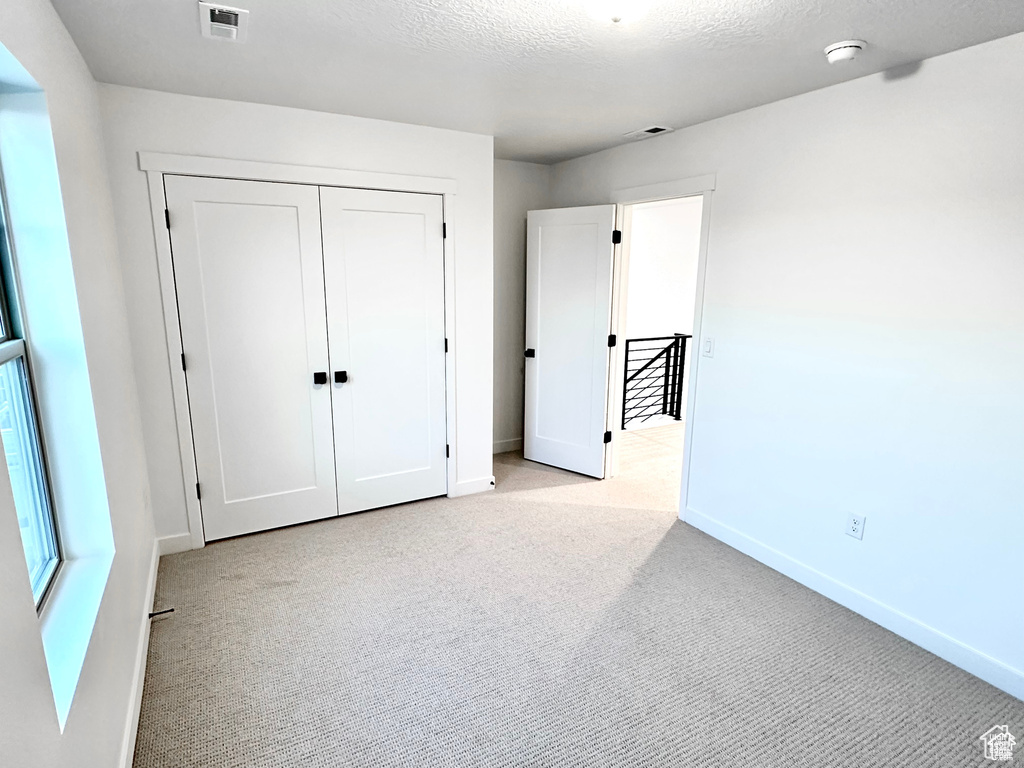 Unfurnished bedroom featuring carpet floors, baseboards, a closet, and a textured ceiling