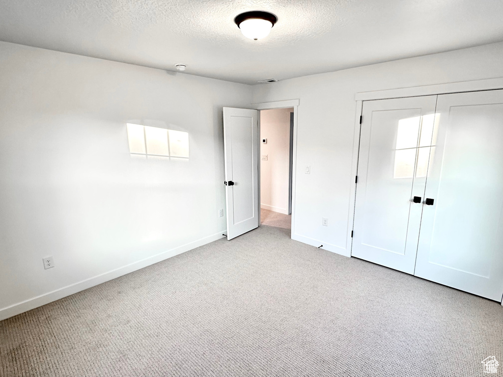 Unfurnished bedroom featuring carpet floors, baseboards, a closet, and a textured ceiling