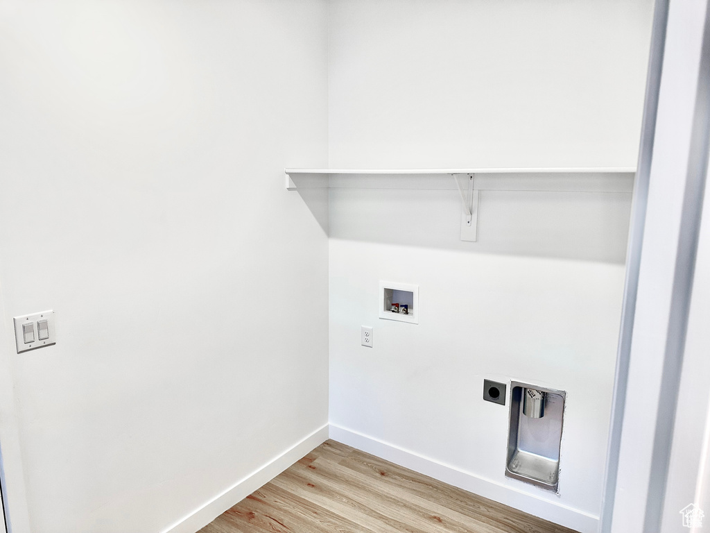 Washroom with light wood-type flooring, hookup for a washing machine, baseboards, and hookup for an electric dryer