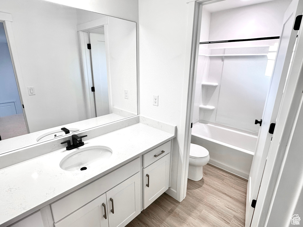 Bathroom featuring toilet, vanity, wood finished floors, and shower / bath combination