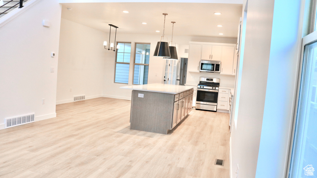 Kitchen with stainless steel appliances, light wood finished floors, a center island, recessed lighting, and baseboards