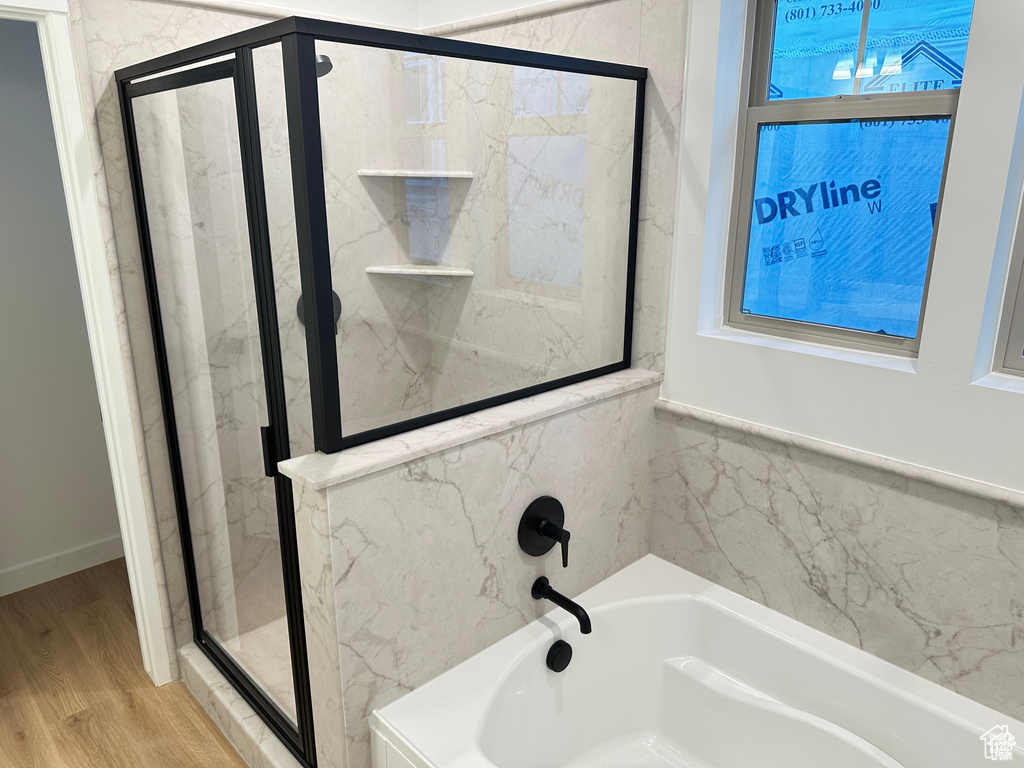 Bathroom with a garden tub, a marble finish shower, and wood finished floors