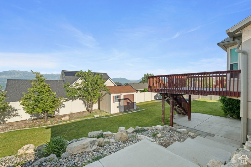 View of yard with a deck with mountain view, stairway, and a patio