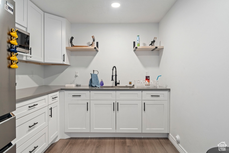 Kitchen with open shelves, a sink, light wood-style floors, white cabinets, and recessed lighting