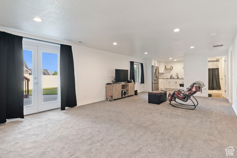 Living area with light colored carpet, plenty of natural light, recessed lighting, and french doors